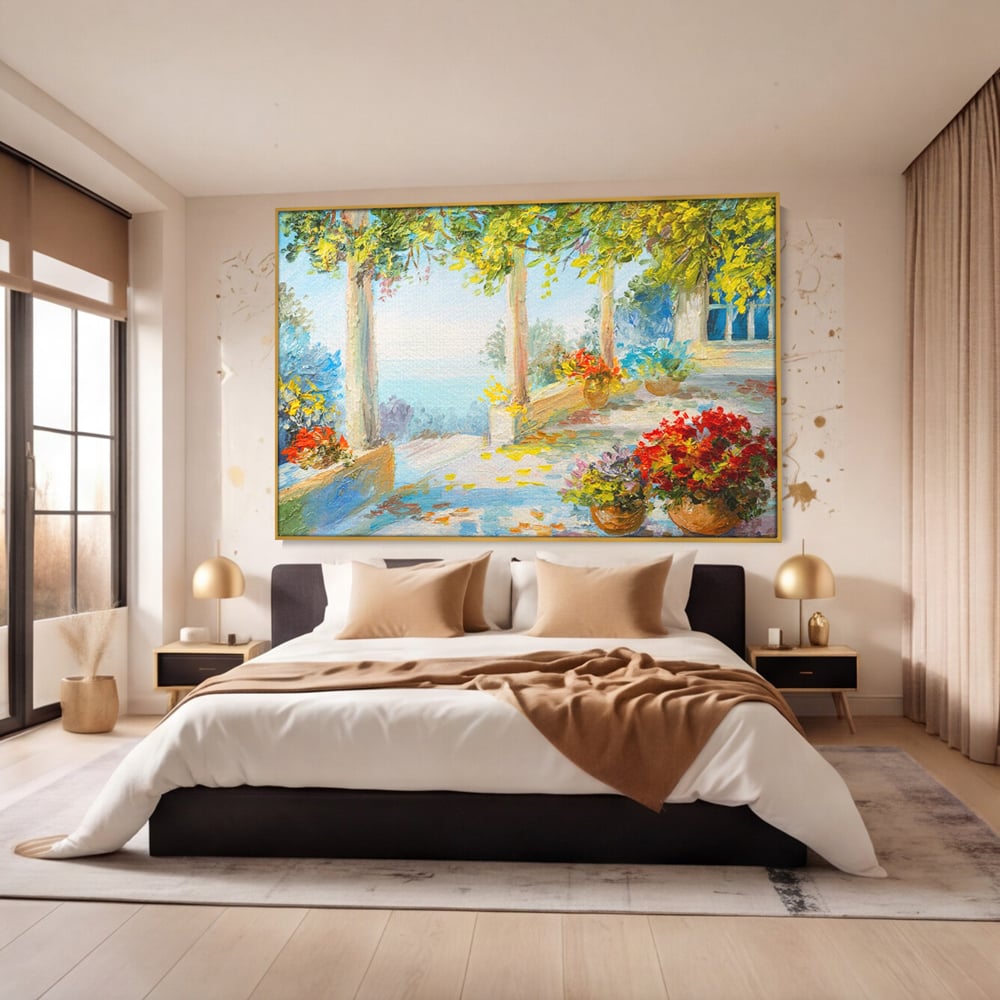 Tablou canvas cu pictura terasa insorita cu flori rosii, in rama de aluminiu auriu, pe perete intr-un dormitor
