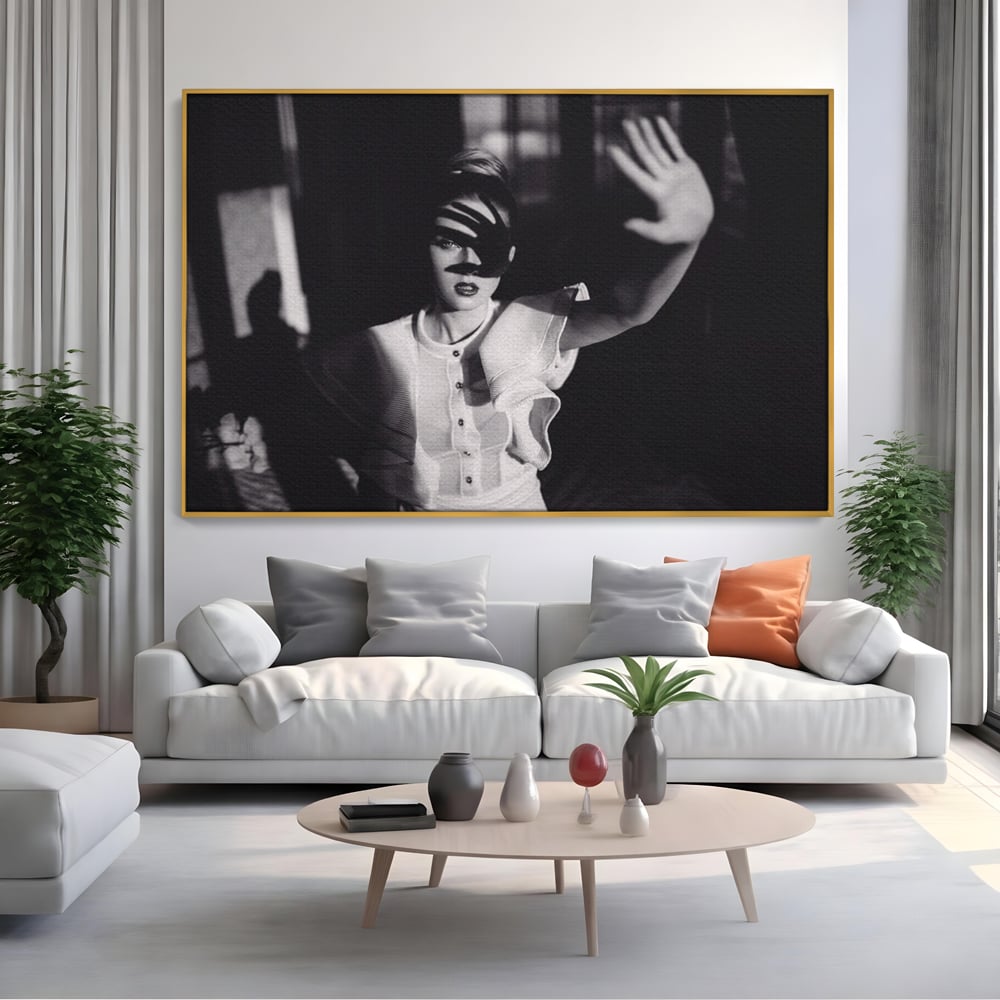 Tablou canvas cu tablou canvas cu femeie in alb si negru, in rama de aluminiu auriu, pe perete intr-un living