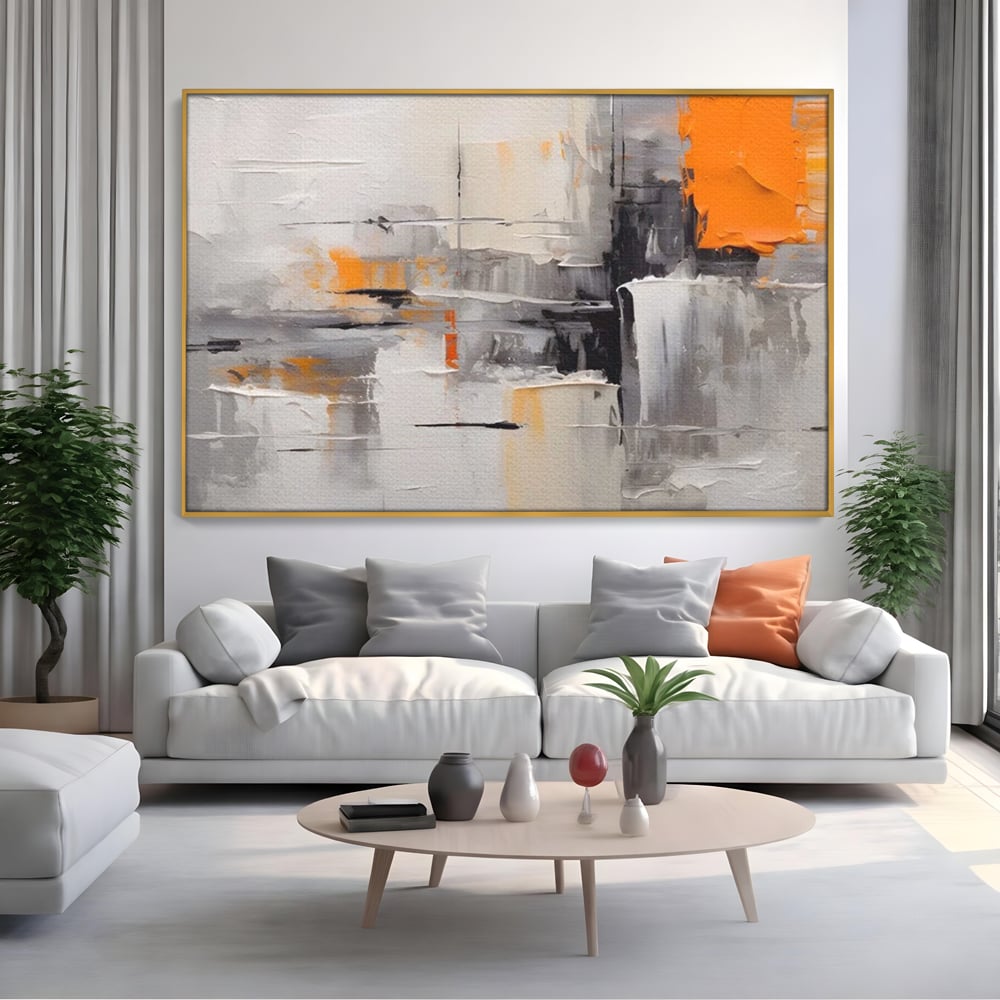 Tablou canvas cu pictura abstracta gri cu pata portocalie, in rama de aluminiu auriu, pe perete intr-un living