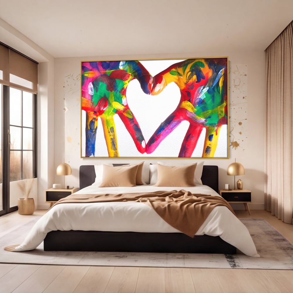 Tablou canvas cu pictura cu maini colorate formand o inima, in rama de aluminiu auriu, pe perete intr-un dormitor