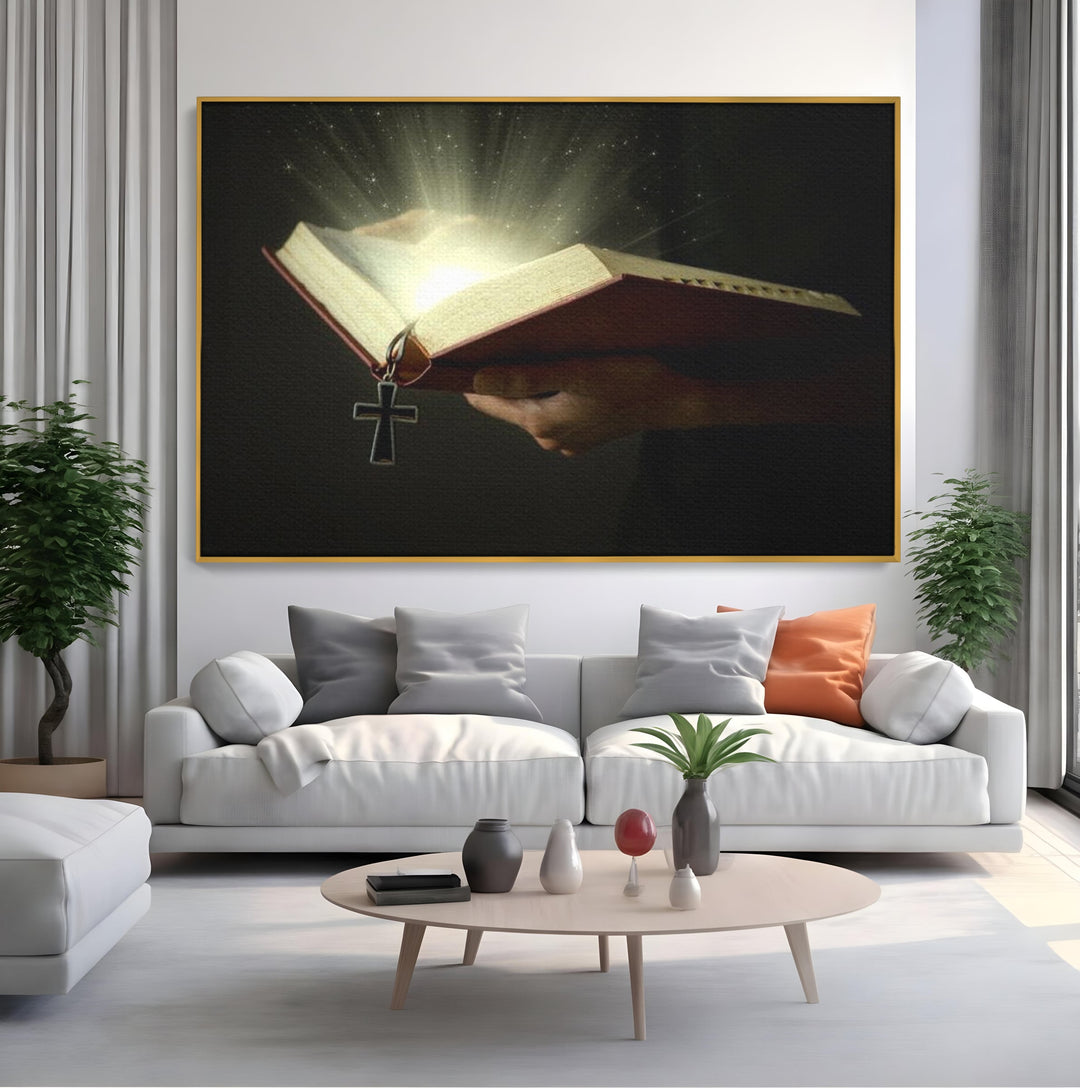 Tablou canvas cu tablou canvas cu biblie deschisa si cruce, in rama de aluminiu auriu, pe perete intr-un living