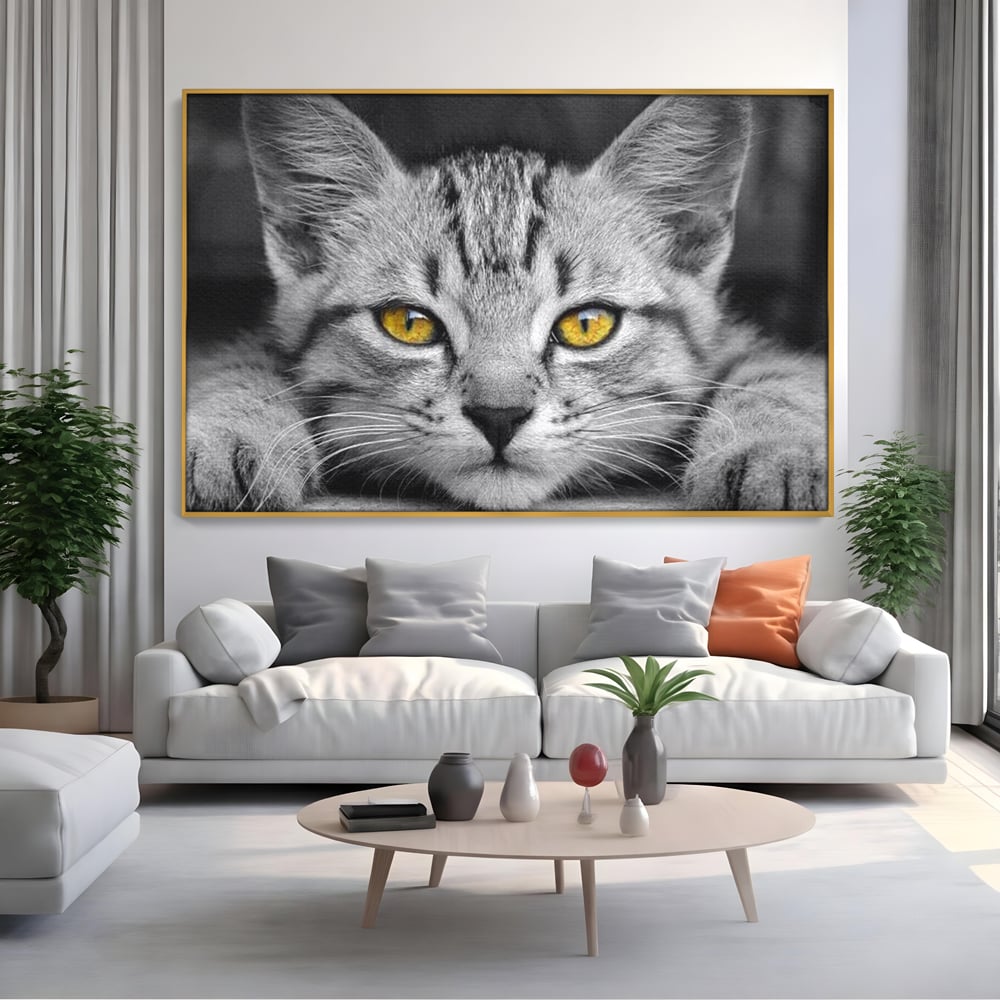 Tablou canvas cu tablou canvas cu o pisica alb-negru si ochi galbeni, in rama de aluminiu auriu, pe perete intr-un living