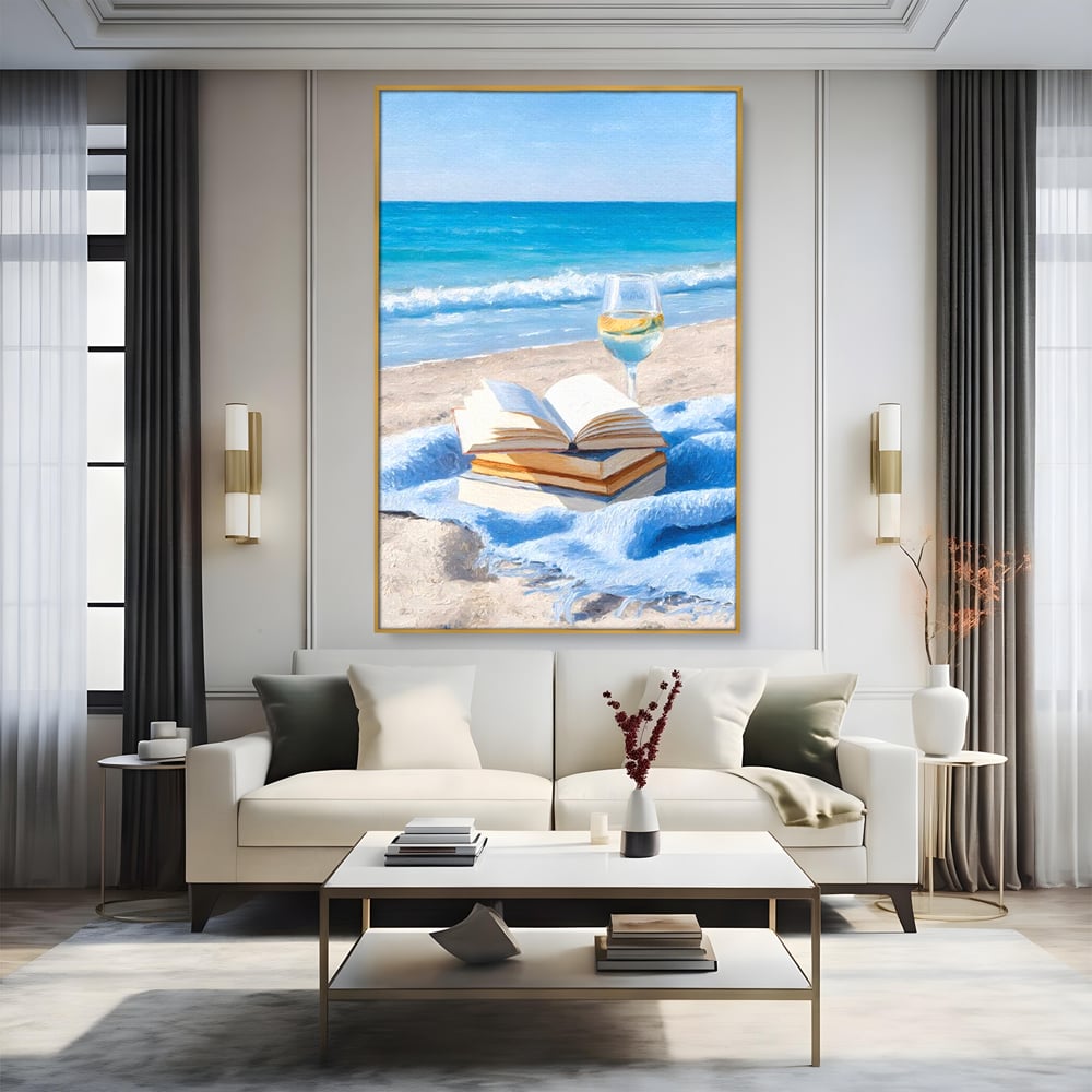 Tablou canvas cu pictura cu carti si pahar de vin pe plaja, in rama de aluminiu auriu, pe perete intr-un living