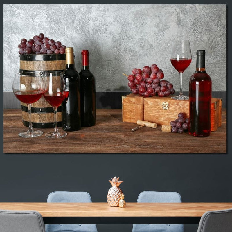 tablou canvas cu trei sticle de vin si pahare cu vin rosu pe o masa de lemn in stil rustic, alaturi de ciorchini de struguri