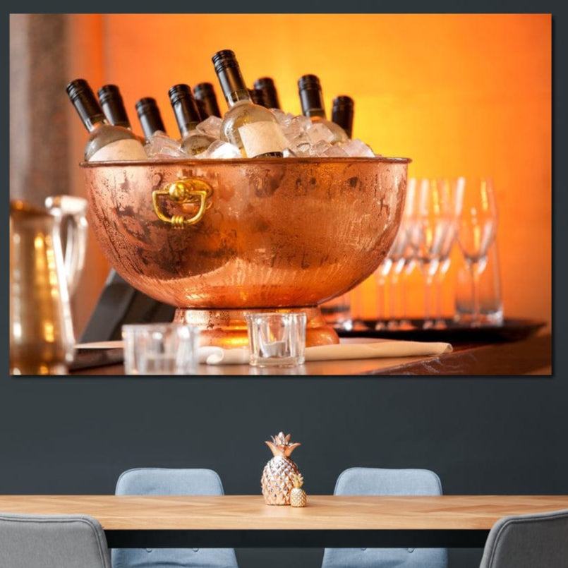 tablou canvas cu o frapiera transparenta cu sticle de vin alb si gheata, pe fundal portocaliu cu pahare si lumina calda