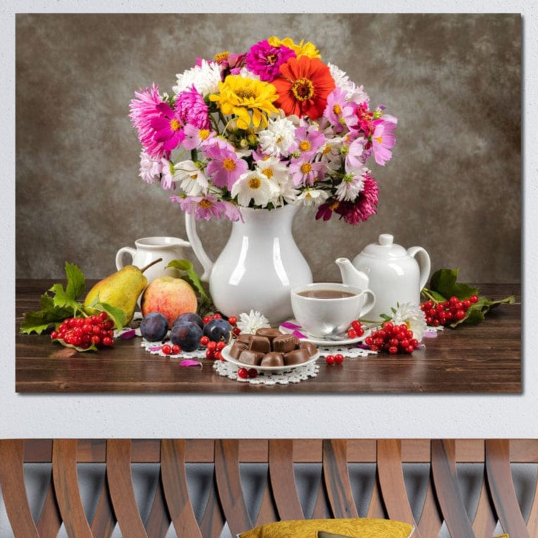 tablou canvas cu o vaza cu flori colorate, pe o masa de lemn cu o ceasca de cafea, fructe si praline de ciocolata