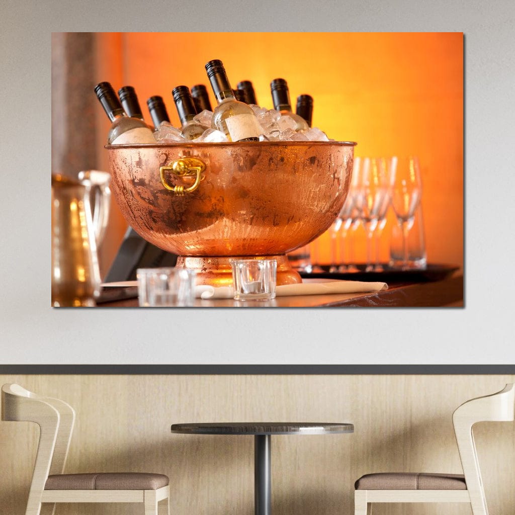 tablou canvas cu o frapiera transparenta cu sticle de vin alb si gheata, pe fundal portocaliu cu pahare si lumina calda