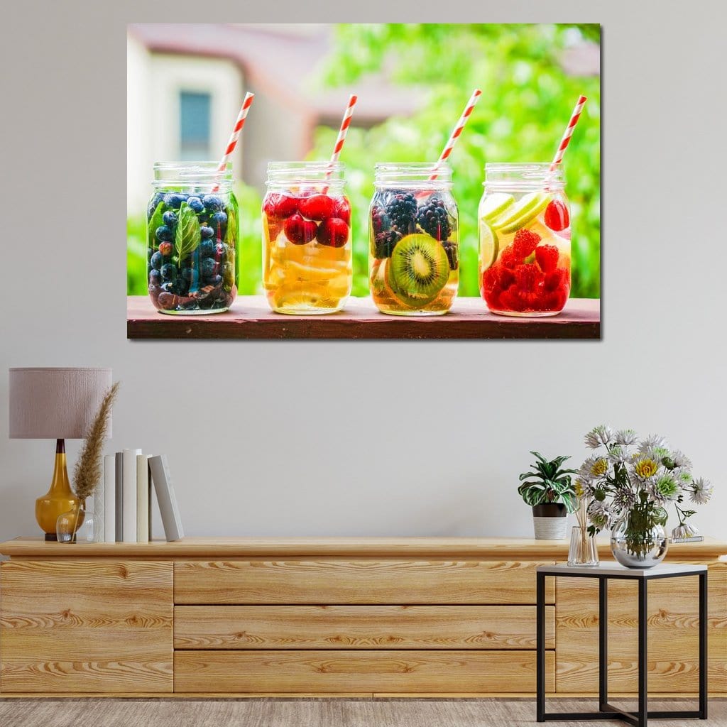 tablou canvas cu patru pahare cu suc si fructe precum afine, cirese, kiwi, zmeura, lamaie, mure si paie colorate, pe fundal cu vegetatie verde