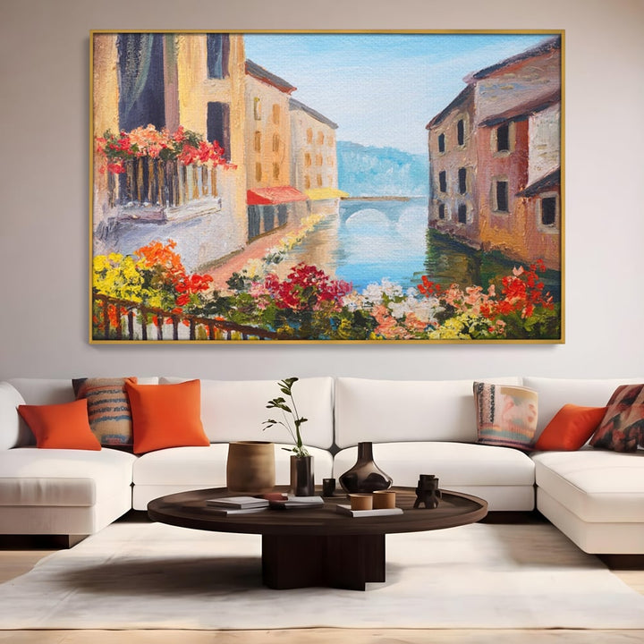 Tablou canvas cu pictura cu canal italian si flori, in rama de aluminiu auriu, pe perete intr-un living