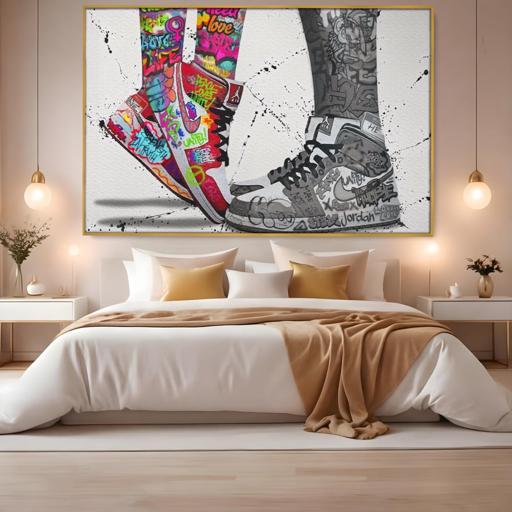 Tablou canvas cu tablou canvas cu adidasi graffiti si picioare, in rama de aluminiu auriu, pe perete intr-un dormitor