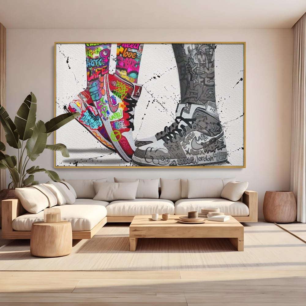 Tablou canvas cu tablou canvas cu adidasi graffiti si picioare, in rama de aluminiu auriu, pe perete intr-un living