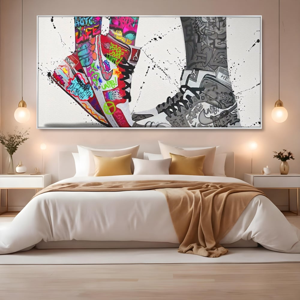 Tablou canvas cu tablou canvas cu adidasi graffiti si picioare, in rama de aluminiu argintiu, pe perete intr-un dormitor