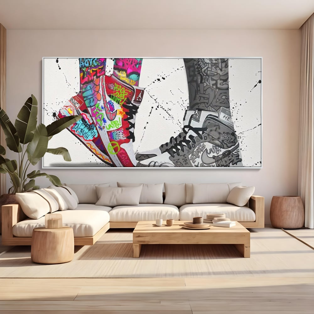 Tablou canvas cu tablou canvas cu adidasi graffiti si picioare, in rama de aluminiu argintiu, pe perete intr-un living