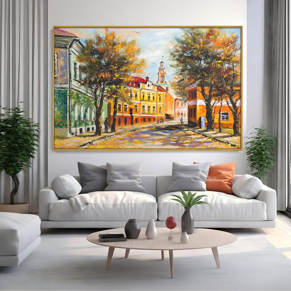 Tablou canvas cu pictura stradala cu peisaj de toamna, in rama de aluminiu auriu, pe perete intr-un living