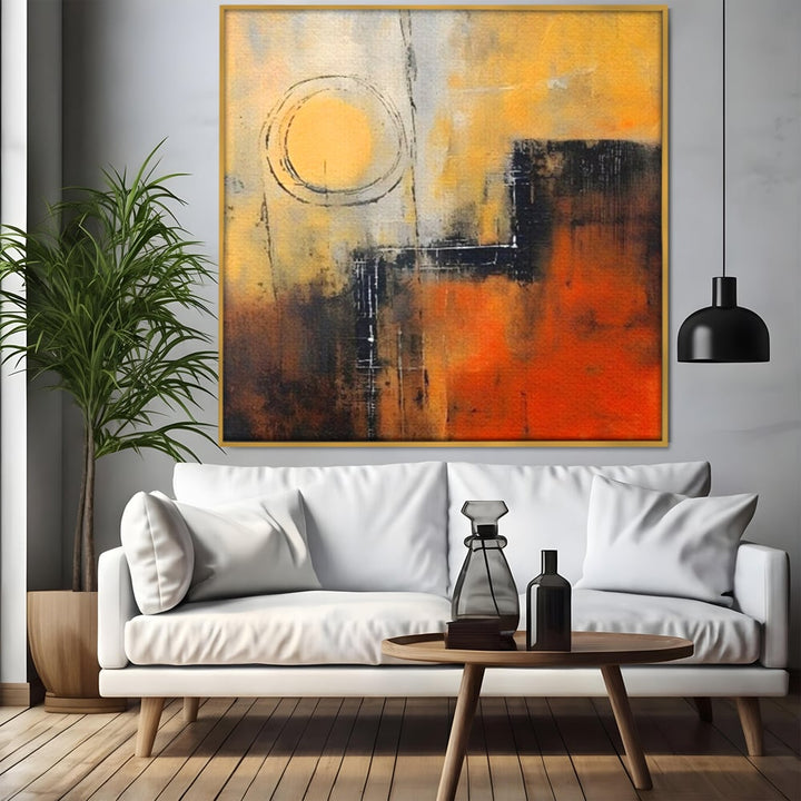 Tablou canvas cu pictura abstracta cu cerc galben, in rama de aluminiu auriu, pe perete intr-un living
