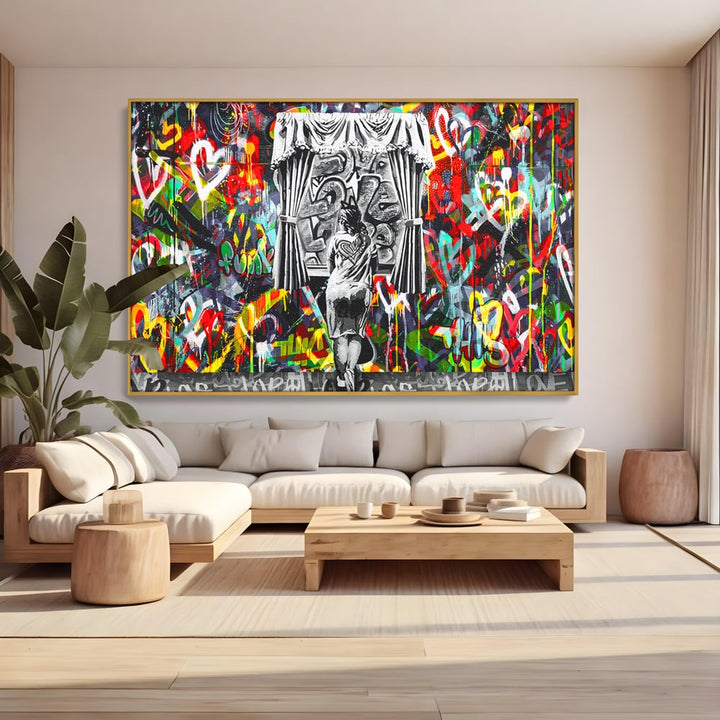 Tablou canvas cu tablou canvas cu graffiti urban si o silueta, in rama de aluminiu auriu, pe perete intr-un living