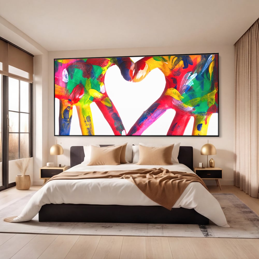 Tablou canvas cu pictura cu maini colorate formand o inima, in rama de aluminiu negru, pe perete intr-un dormitor
