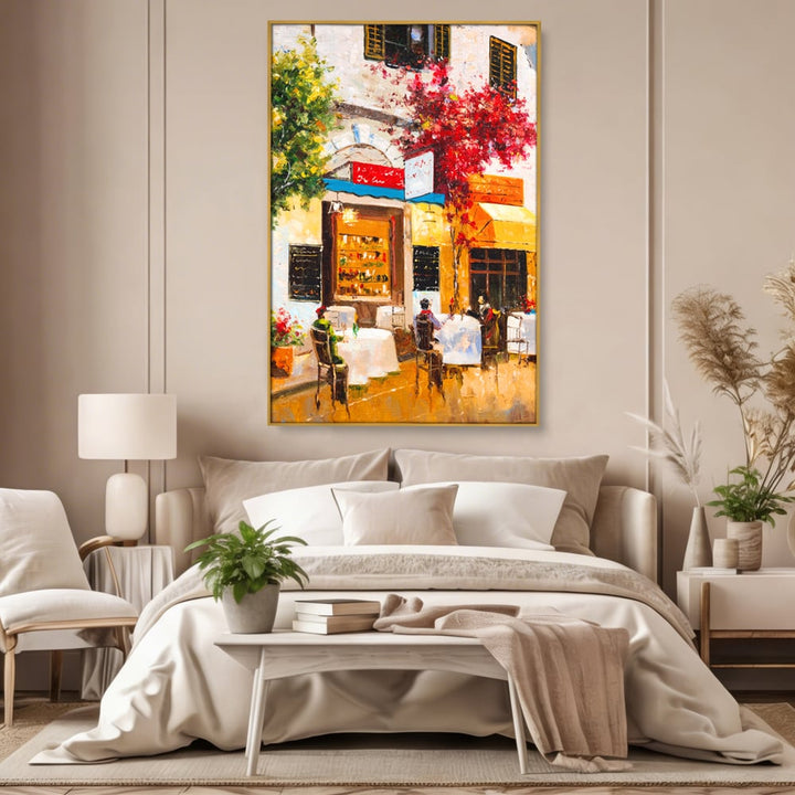 Tablou canvas cu pictura stradala cu terasa, in rama de aluminiu auriu, pe perete intr-un dormitor