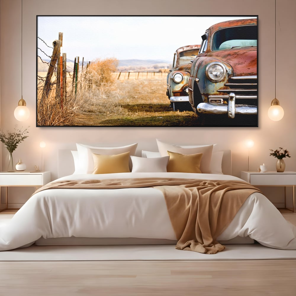 Tablou canvas cu doua masini ruginite pe un camp uscat, in rama de aluminiu negru, pe perete intr-un dormitor