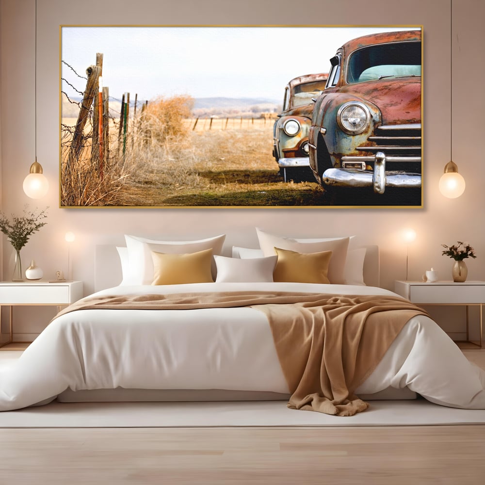 Tablou canvas cu doua masini ruginite pe un camp uscat, in rama de aluminiu auriu, pe perete intr-un dormitor