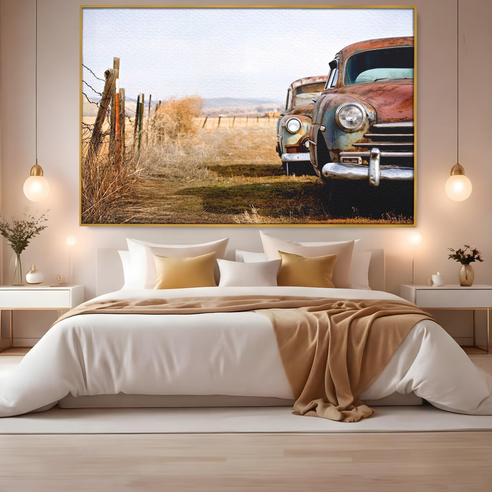 Tablou canvas cu doua masini ruginite pe un camp uscat, in rama de aluminiu auriu, pe perete intr-un dormitor