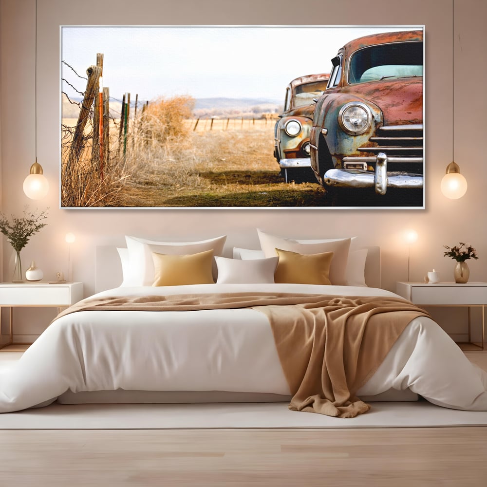 Tablou canvas cu doua masini ruginite pe un camp uscat, in rama de aluminiu argintiu, pe perete intr-un dormitor