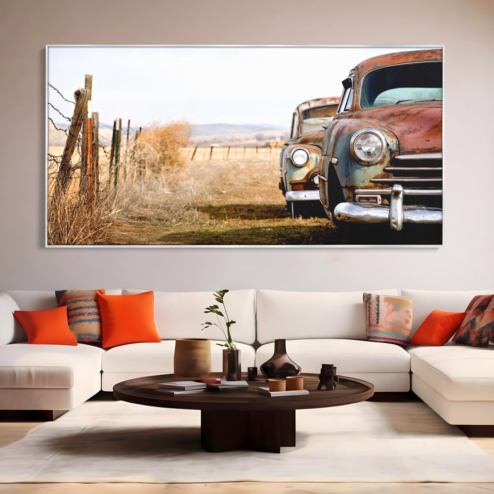 Tablou canvas cu doua masini ruginite pe un camp uscat, in rama de aluminiu argintiu, pe perete intr-un living