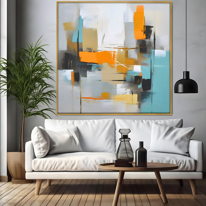 Tablou canvas cu pictura abstracta cu forme geometrice, in rama de aluminiu auriu, pe perete intr-un living