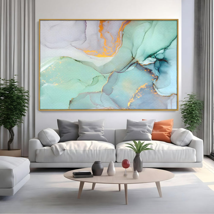 Tablou canvas cu pictura abstracta cu efect de marmura colorata, in rama de aluminiu auriu, pe perete intr-un living