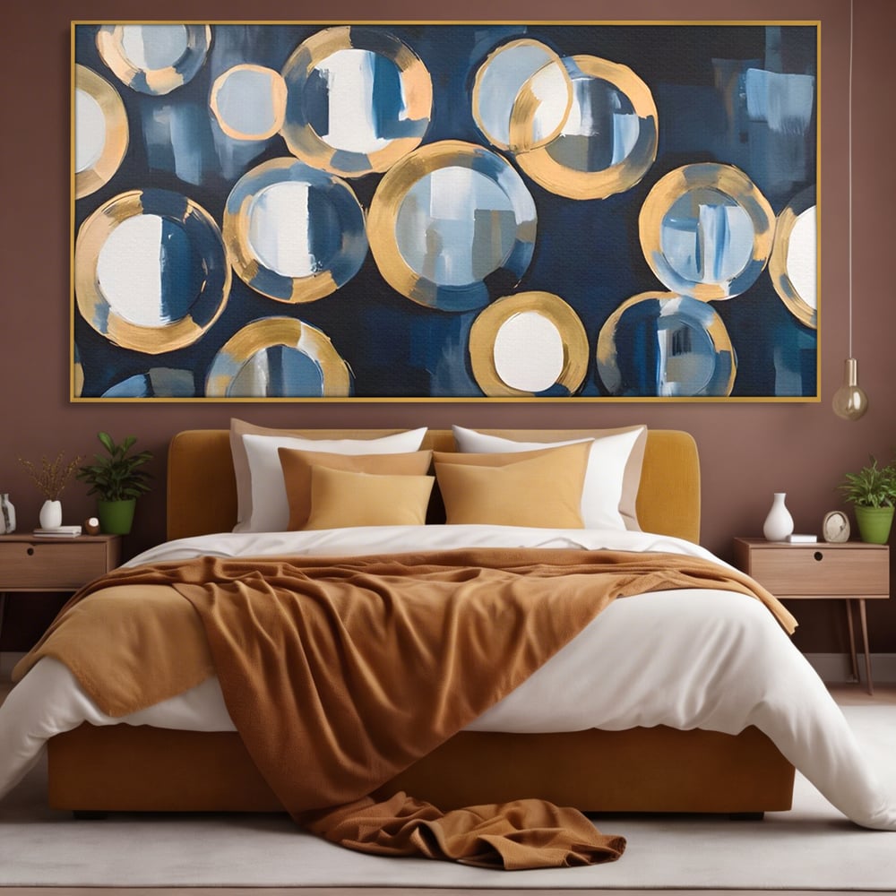 Tablou canvas cu pictura abstracta cu cercuri albastre si aurii, in rama de aluminiu auriu, pe perete intr-un dormitor