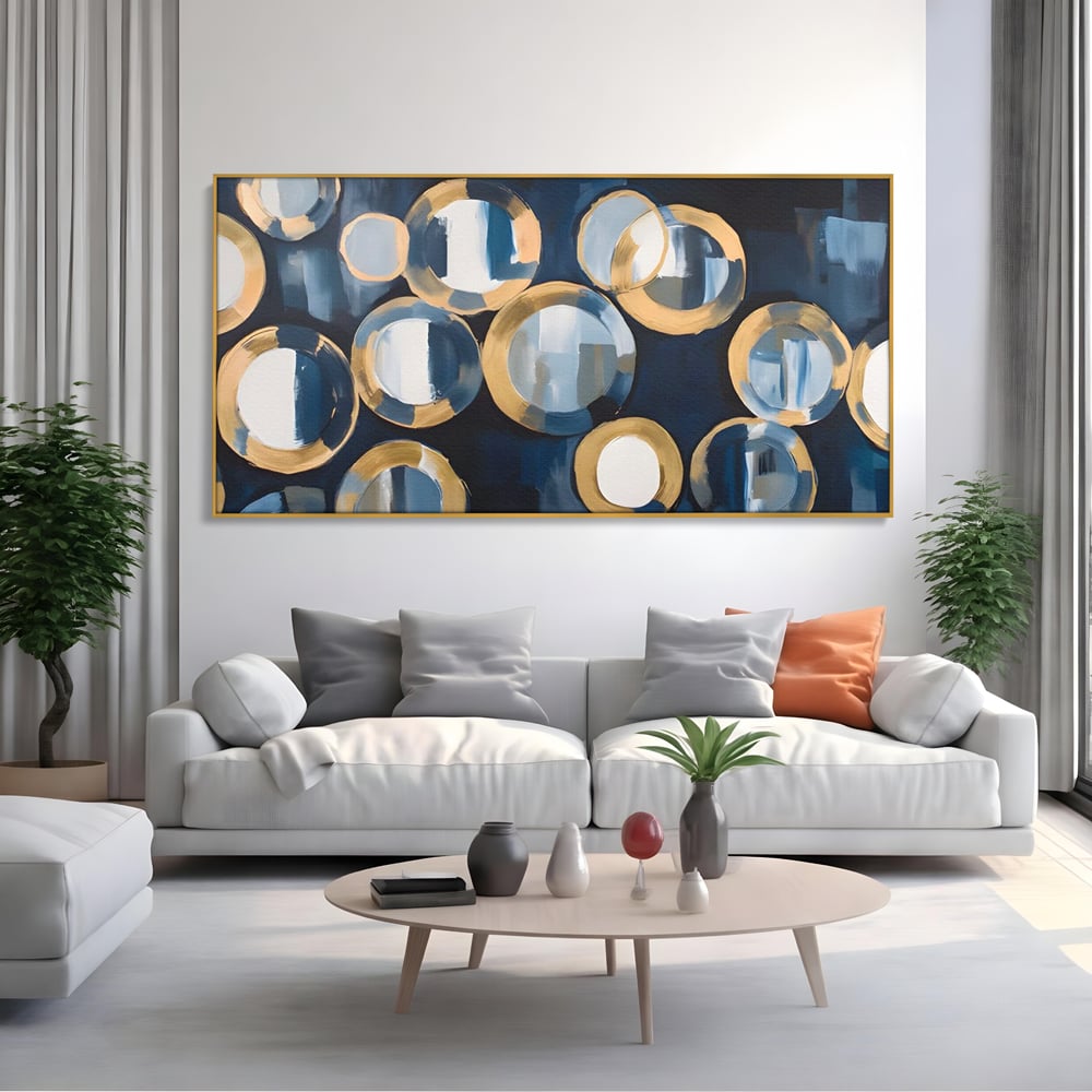 Tablou canvas cu pictura abstracta cu cercuri albastre si aurii, in rama de aluminiu auriu, pe perete intr-un living