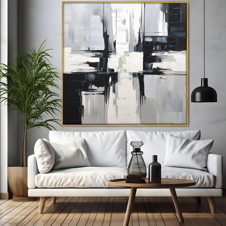 Tablou canvas cu pictura abstracta alb-negru, in rama de aluminiu auriu, pe perete intr-un living