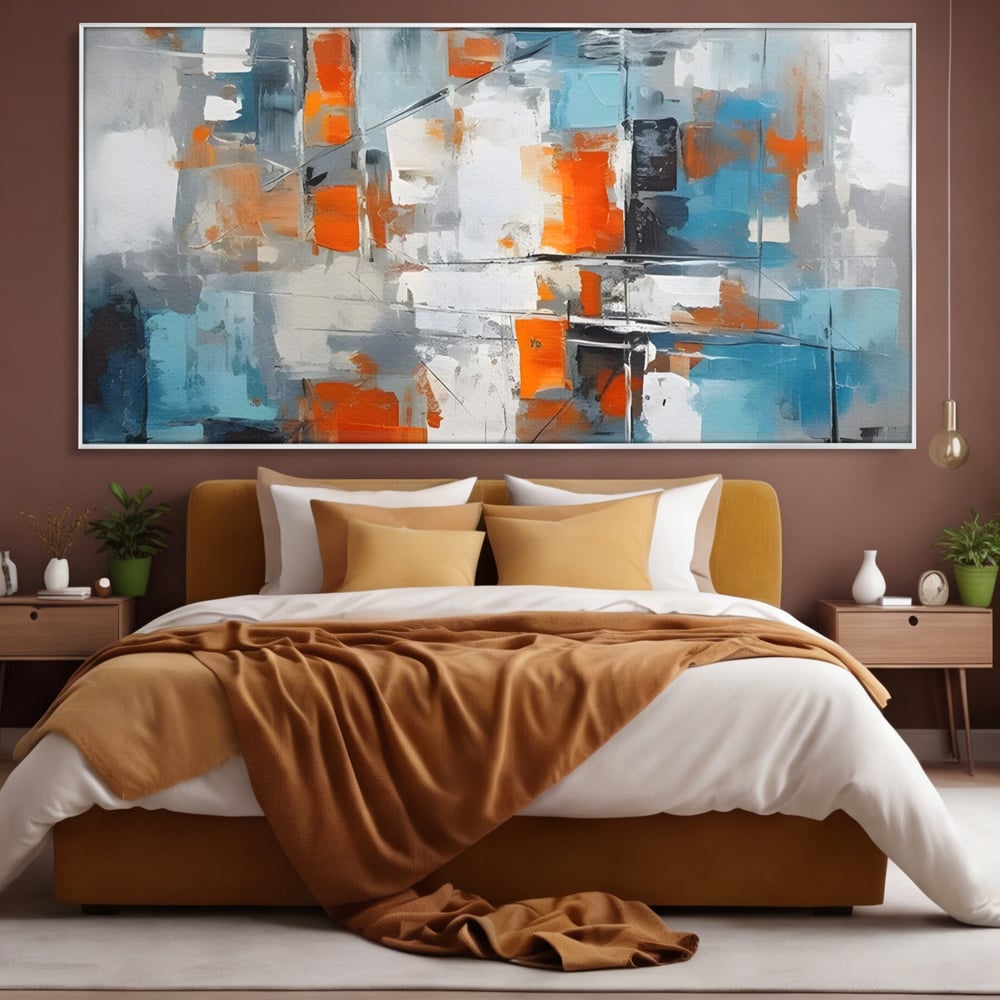 Tablou canvas cu pictura abstracta cu blocuri portocalii si albastre, in rama de aluminiu argintiu, pe perete intr-un dormitor