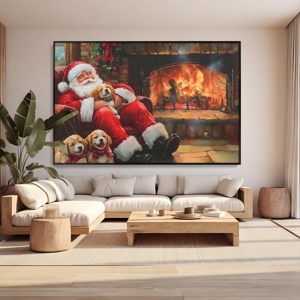 Tablou canvas cu mos craciun dormind cu catei langa semineu, in rama de aluminiu negru, pe perete intr-un living