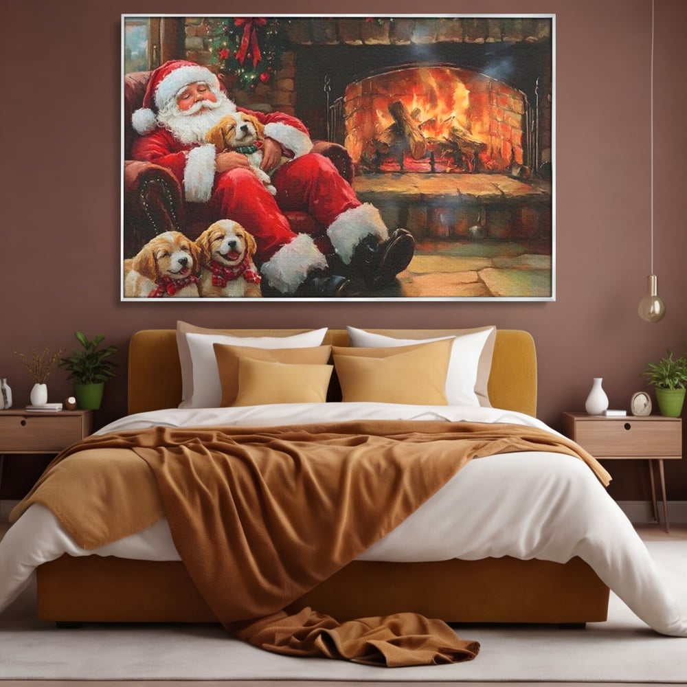 Tablou canvas cu mos craciun dormind cu catei langa semineu, in rama de aluminiu argintiu, pe perete intr-un dormitor
