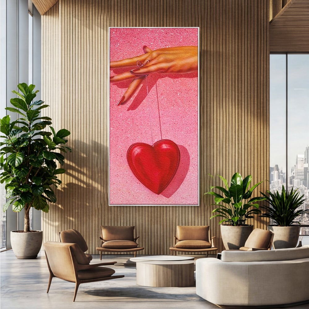 Tablou canvas cu ilustratie cu mana care tine o inima rosie, in rama de aluminiu argintiu, pe perete intr-un birou