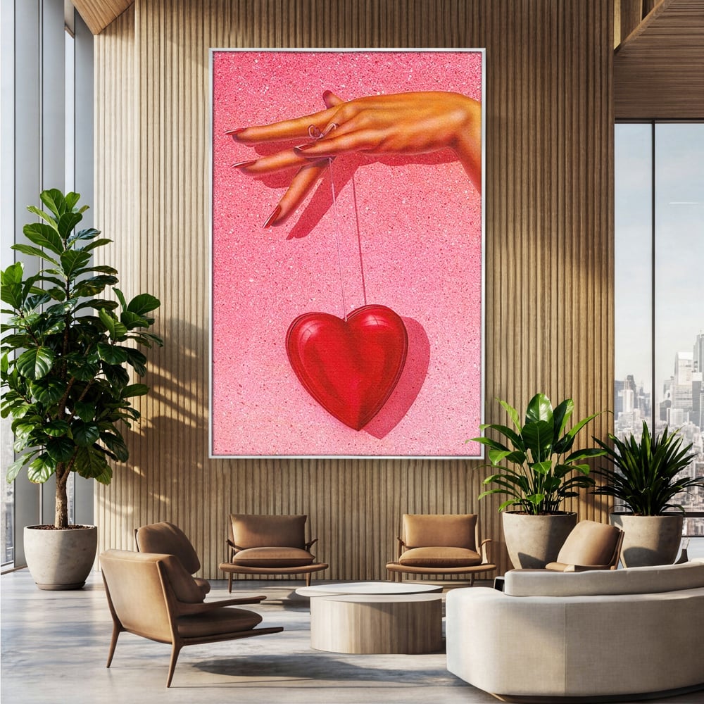 Tablou canvas cu ilustratie cu mana care tine o inima rosie, in rama de aluminiu argintiu, pe perete intr-un birou