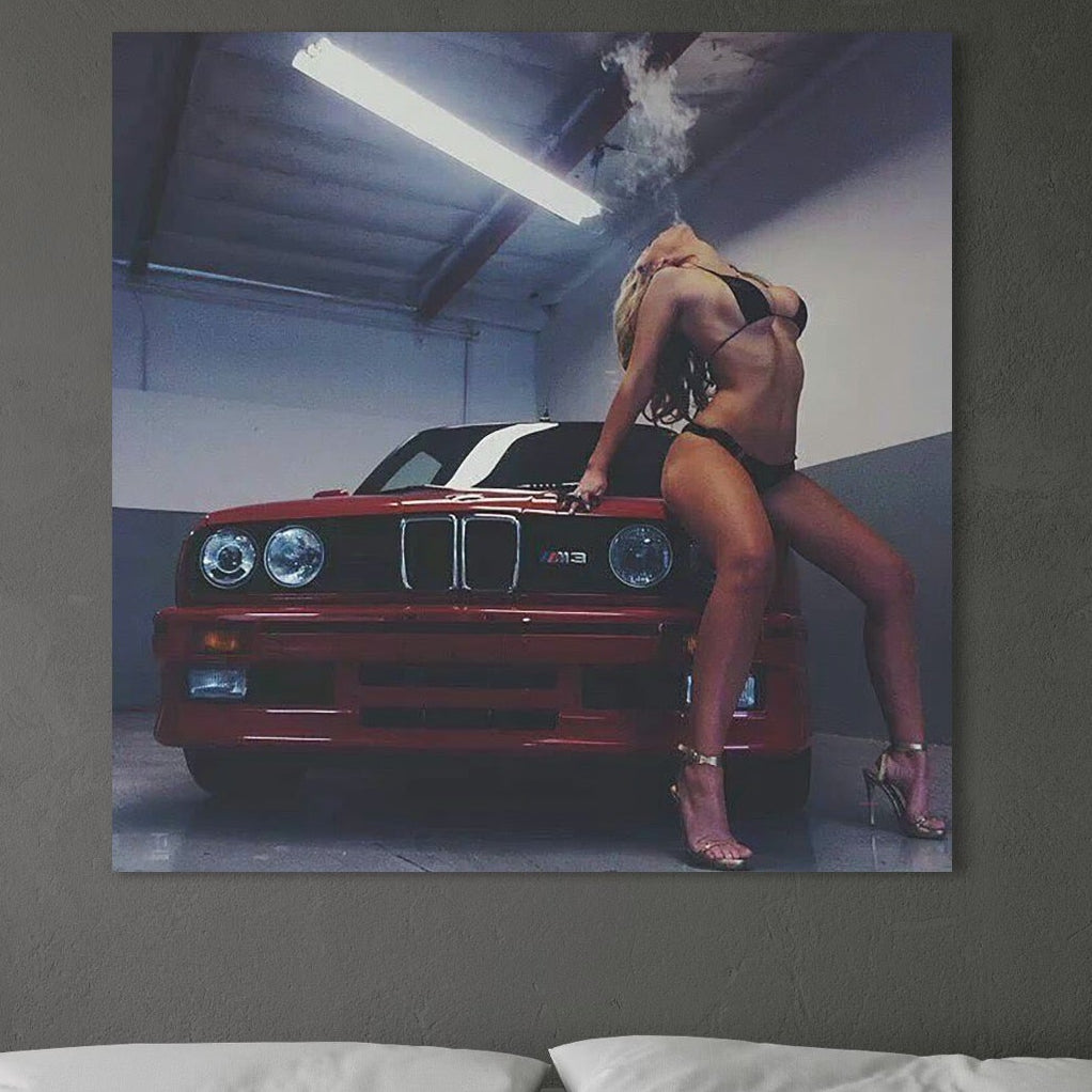 tablou canvas cu o femeie intr-un costum de baie provocator, pe o masina rosie, intr-un garaj iluminat