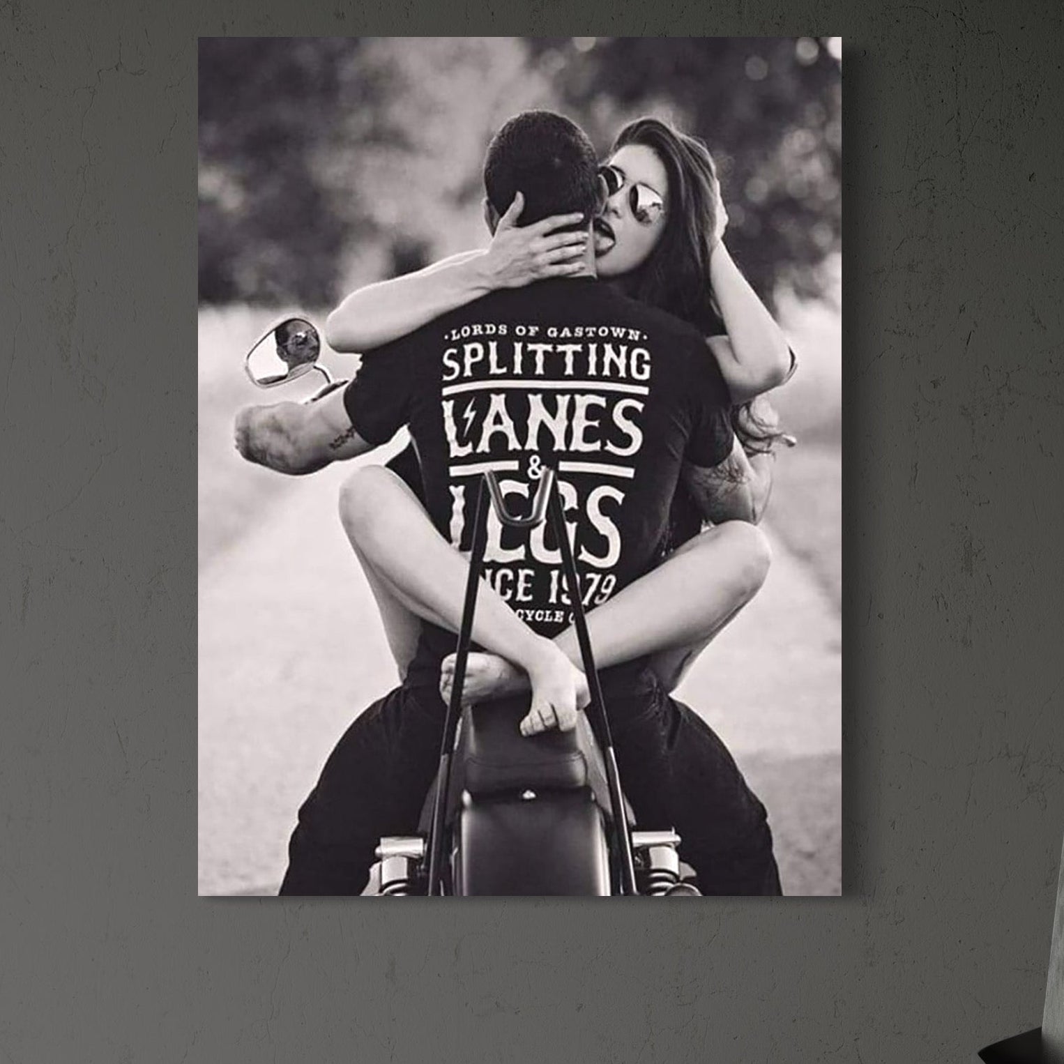 tablou canvas cu o femeie cu ochelari de soare si un barbat imbratisati pe o motocicleta, intr-un cadru  retro alb si negru