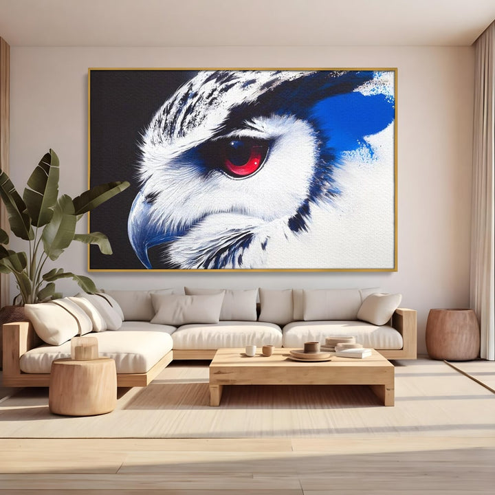 Tablou canvas cu tablou canvas cu ochi de bufnita si iris rosu, in rama de aluminiu auriu, pe perete intr-un living