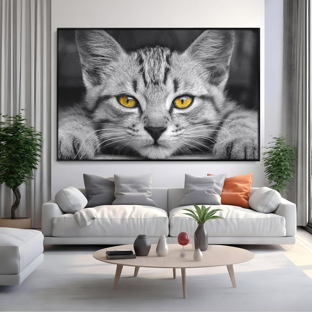 Tablou canvas cu tablou canvas cu o pisica alb-negru si ochi galbeni, in rama de aluminiu negru, pe perete intr-un living