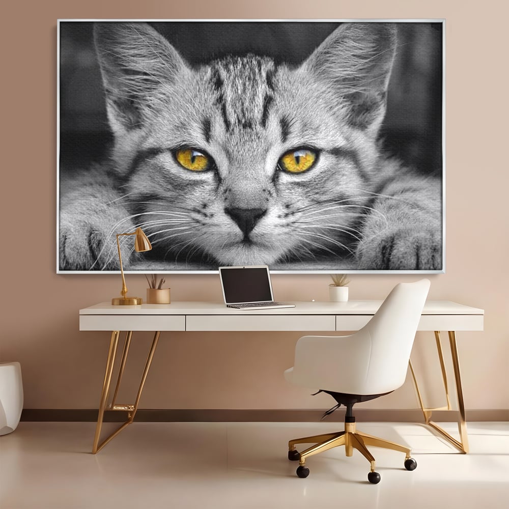 Tablou canvas cu tablou canvas cu o pisica alb-negru si ochi galbeni, in rama de aluminiu argintiu, pe perete intr-un birou