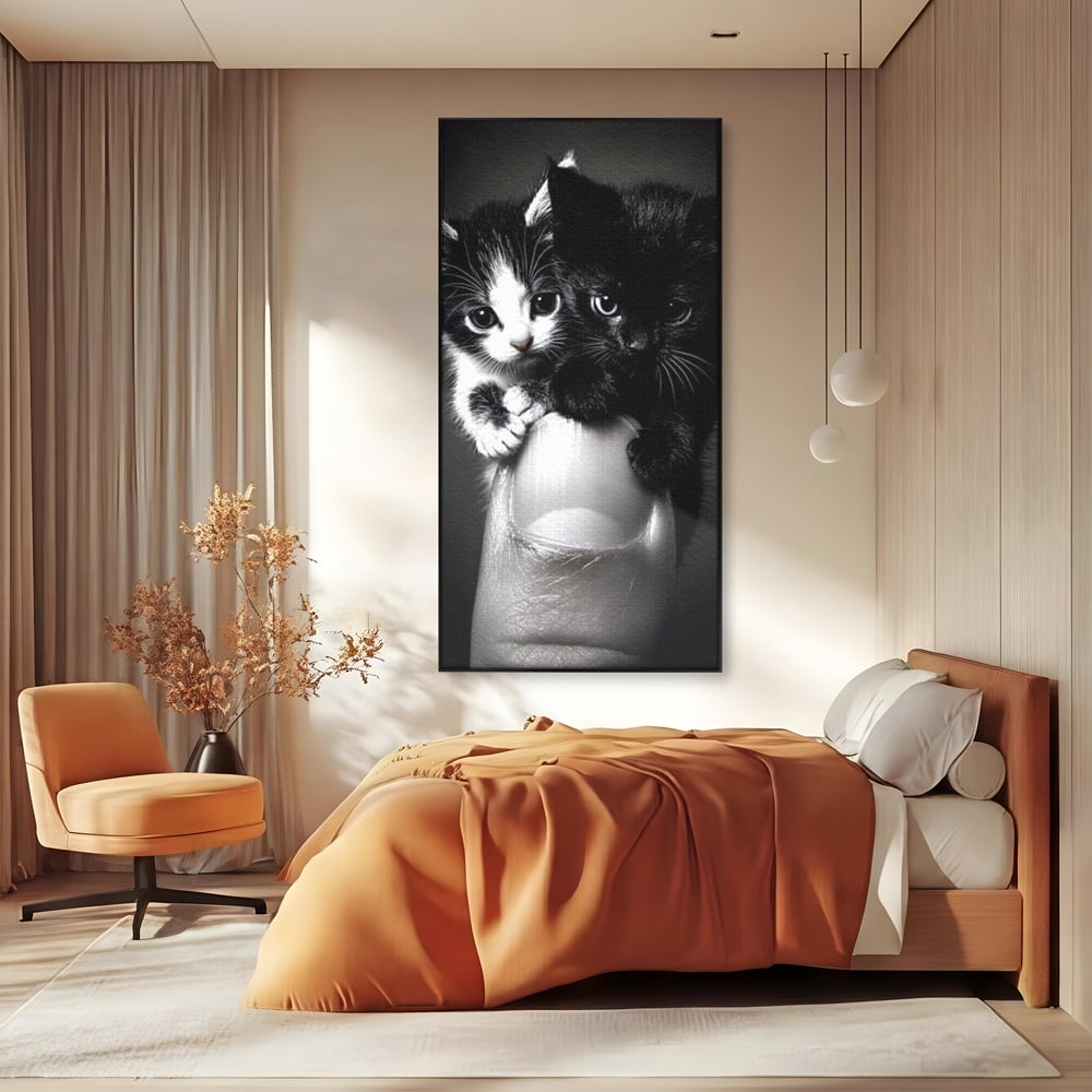 Tablou canvas cu tablou canvas cu doi pisoi mici agatati de un deget, in rama de aluminiu negru, pe perete intr-un dormitor