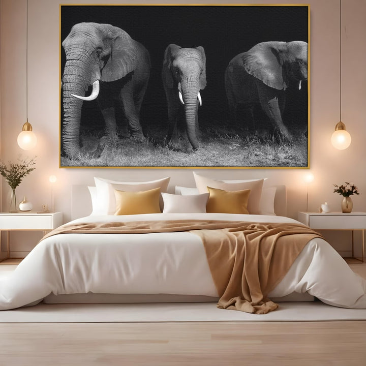 Tablou canvas cu trei elefanti pe fundal negru, in rama de aluminiu auriu, pe perete intr-un dormitor