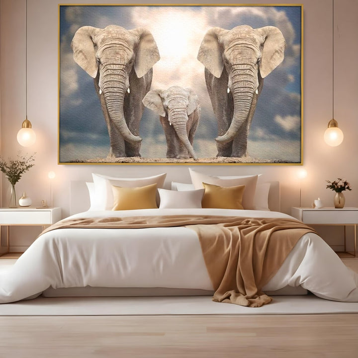 Tablou canvas cu tablou canvas cu trei elefanti, in rama de aluminiu auriu, pe perete intr-un dormitor