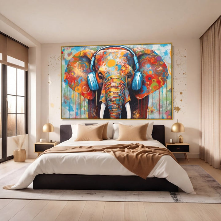 Tablou canvas cu pictura cu elefant colorat si casti, in rama de aluminiu auriu, pe perete intr-un dormitor