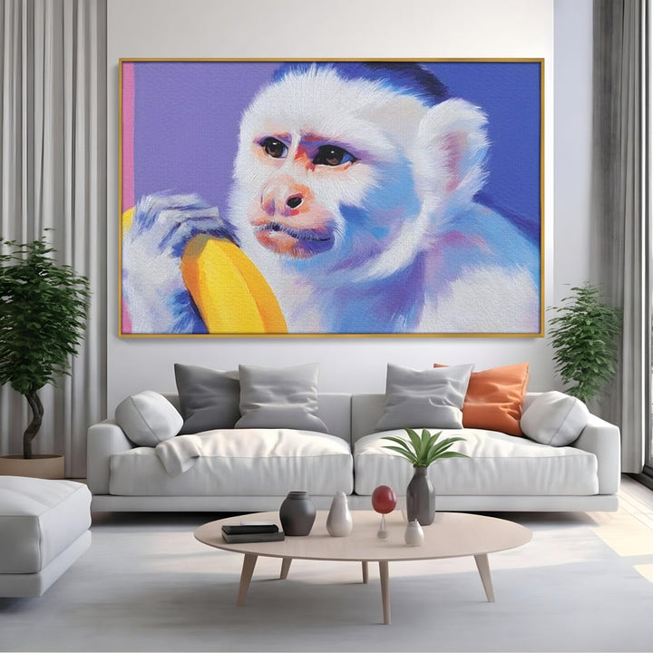 Tablou canvas cu tablou canvas cu maimuta pop art si banana, in rama de aluminiu auriu, pe perete intr-un living
