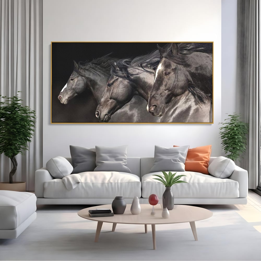 Tablou canvas cu tablou canvas cu trei cai negri in galop, in rama de aluminiu auriu, pe perete intr-un living