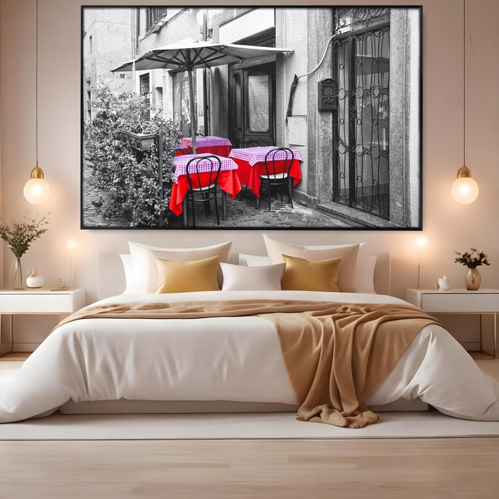 Tablou canvas cu cafenea stradala vintage alb negru cu pete de rosu, in rama de aluminiu negru, pe perete intr-un dormitor