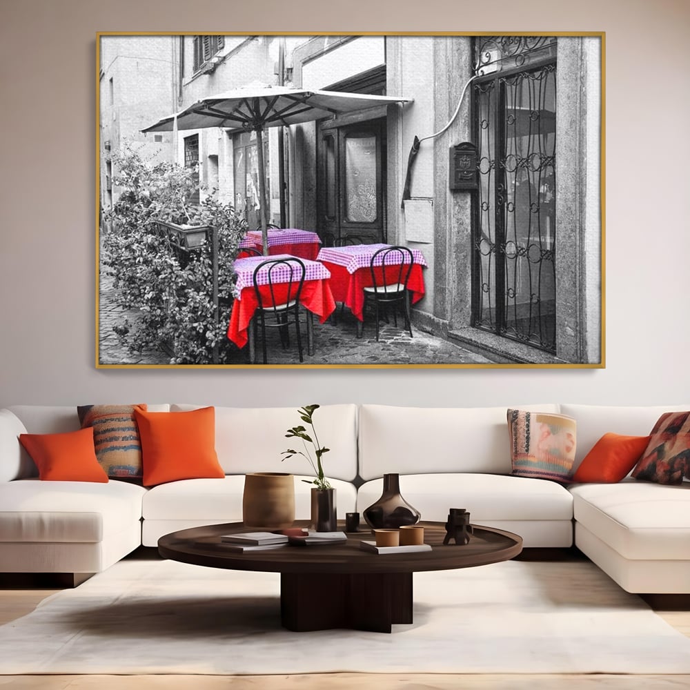 Tablou canvas cu cafenea stradala vintage alb negru cu pete de rosu, in rama de aluminiu auriu, pe perete intr-un living